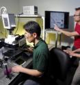 Georgia Tech graduate students Kwanghun Chung and Matthew Crane, and assistant professor Hang Lu (left to right), set up the microchip on the microscope and observe a live image of it on the monitor.