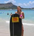 A girl holds the surfboard reactor on a beach in Hawaii.