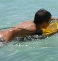 A boy paddling on the surfboard reactor in the sea in Hawaii.