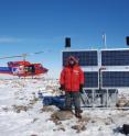 Eric Kendrick, a senior research associate at Ohio State, shown at a POLENET GPS site in West Antarctica.  He is standing in front of solar panels, battery boxes, and wind generators used to power the GPS station.