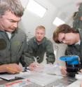 University of Utah chemist Lorraine Siperko (right) works on a water quality monitoring system while experiencing weightless conditions at the top of an arc-shaped flight path by a NASA C-9 research plane nicknamed the "vomit comet." Other scientists working on the project include Bob Lipert of Iowa State University (left) and John Straub of Wyle Laboratories.