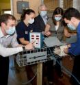 The Georgia Tech team that developed the Gorilla Tough Cuff and a Zoo Atlanta trainer position the pressure cuff casing inside the rectangular mesh trap so that a gorilla's blood pressure can be measured.