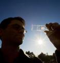 Sandia project lead Greg Nielson holds a solar cell test prototype with a microscale lens array fastened above it. Together, the cell and lens help create a concentrated photovoltaic unit.