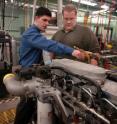 Gregory M. Shaver, from left, an assistant professor of mechanical engineering at Purdue, and graduate student David Snyder discuss how to modify a commercial diesel engine with a new technique that promises to reduce emissions of nitrogen oxides for engines running on biodiesel. Graduate student Gayatri Adi (background) reviews software algorithms needed for the new technology.