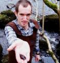 Queen's conservation scientist Conor Wilson pictured with one of the tagged freshwater mussels released back into the river as part of a 12-year research project.