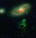 The green Voorwerp in the foreground remains illuminated by light emitted up to 70,000 years ago by a quasar in the center of the background galaxy, which has since died out.