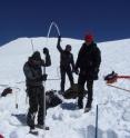 Researchers are installing an ablation stick, near a recently dug snow pit, to help in establishing the mass balance of the ice field.