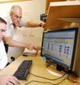 Prof. John McDonald (standing) and postdoctoral fellow Ken Scarberry examine statistical data from their study of a potential new treatment option for ovarian cancer.