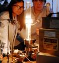 Georgia Tech graduate students Yike Hu and John Hankinson observe a high-temperature furnace used to produce epitaxial graphene on a silicon carbide wafer.  A new "templated growth" technique allows fabrication of nanoribbons with smooth edges and high conductivity.