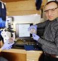 Georgia Tech biology graduate student Chengwei Luo (left) and civil and environmental engineering assistant professor Kostas Konstantinidis display petri dishes showing that strains of commensal <I>E. coli </I>and environmental <I>E. coli</I> both grow on the media used for the fecal coliform test. Analyzing the genomes of the strains -- shown on the computer monitor -- is the only way the researchers can tell these two groups of <I>E. coli</I> apart.