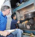 Paul Steffes, a professor in Georgia Tech's School of Electrical and Computer Engineering, and graduate student Danny Duong, examine instrumentation on a pressure vessel used to simulate the atmosphere of Jupiter.