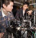 Graduate student Xibo Zhang (left) and Cheng Chin (right), associate professor in physics, examine experimental hardware in Chin's ultracold laboratory at the University of Chicago. Zhang began working with Chin because of their mutual interest in quantum simulation, the idea that one type of quantum system, such as ultracold atoms in a laboratory setting, could be used to simulate another system, like the one that dominated the universe shortly after the big bang.