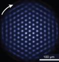 The NIST quantum simulator permits study of quantum systems that are difficult to study in the laboratory and impossible to model with a supercomputer. The heart of the simulator is a two-dimensional crystal of beryllium ions (blue spheres in the graphic); the outermost electron of each ion is a quantum bit (qubit, red arrows). The ions are confined by a large magnetic field in a device called a Penning trap (not shown). Inside the trap the crystal rotates clockwise. The NIST quantum simulator permits study of quantum systems that are difficult to study in the laboratory and impossible to model with a supercomputer. In this photograph of the crystal, the ions are fluorescing, indicating the qubits are all in the same state. Under the right experimental conditions, the ion crystal spontaneously forms this nearly perfect triangular lattice structure.