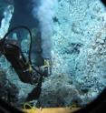 The research submarine Alvin reaches with its mechanical arm to a high-temperature black smoker at the Endeavour Segment, Juan de Fuca Ridge, to study methanogenic microbes.