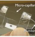 This image shows a microfluidic optomechanical capillary resonator with fluid control tubing.