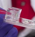 Yi Zhao, associate professor of biomedical engineering and ophthalmology at Ohio State University, holds a prototype polymer lens (center) that combines features of the human eye and insect eye.