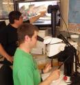 Ricardo Marino-Perez and Derk A. Woller view a grasshopper under the microscope.