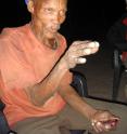 A !Kung Bushman, sporting a Calvin Klein hat, tells stories at a firelight gathering in Africa's Kalahari Desert. University of Utah anthropologist Polly Wiessner has published a new study of the Bushmen suggesting that when firelight extended the day for human ancestors, stories told around the campfire helped stimulate human mental, social and cultural development.