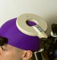 A transcranial magnetic stimulation coil is placed over the part of the brain that controls the receiver's right hand movements.