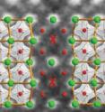 Two mirror-image domains (terbium in green, manganese in red, oxygen not shown) meet at a domain wall, where terbium atoms are squeezed out and replaced by manganese (red cross).