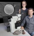 This photo shows Monash University scientists Dr Andrew Tomkins and Dr Sasha Wilson, who were part of the team that have discovered 2.7 billion year old micrometeorites preserved in ancient sedimentary rocks, an example of which is shown in the background. This research team have recognised that fossil micrometeorites sampled the chemistry of the Earth's ancient upper atmosphere, opening a new avenue for investigating atmospheric evolution in deep time.