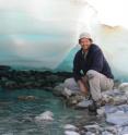 Mark Urban, associate professor of ecology and evolutionary biology at the University of Connecticut, stands under a sheet of aufeis in Alaska. These ice sheets form over Arctic underground springs but have become less prevalent with global warming.
