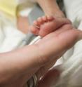 A nurse's fingertips gently touch the foot of a preterm infant in newborn intensive care. Clinical depression during pregnancy increases the risk of premature birth.