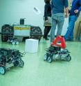 Little robots in Nina Mahmoudian's lab bring power to turn on a light, front left, and wave the white flag on the mini-tank. Adapted to real-world conditions, such robots could restore power to critical infrastructure, like cell towers.